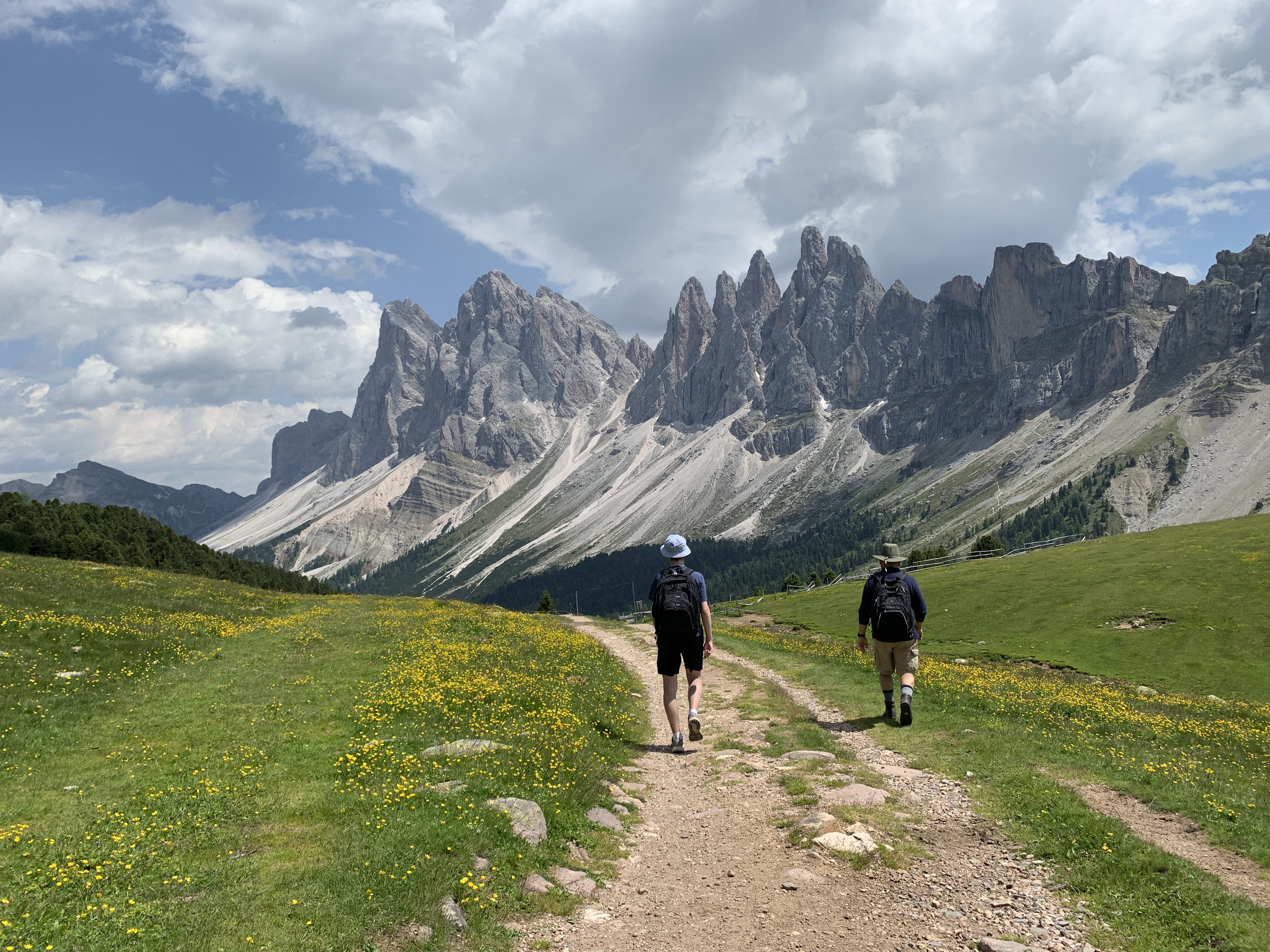 two men walking on a trail with mountains in the background