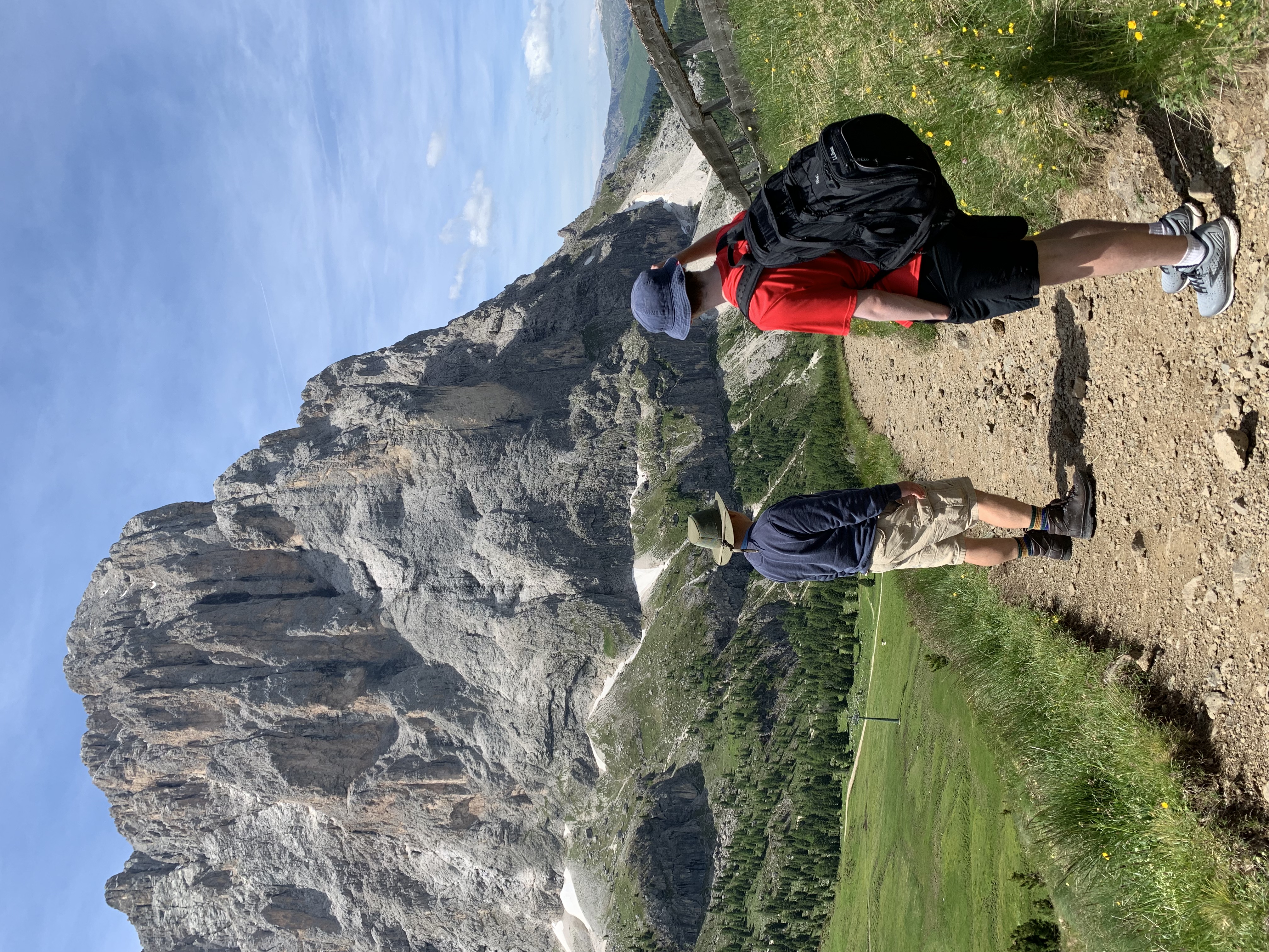 two hikers standing on a trail look at a mountain in the distance