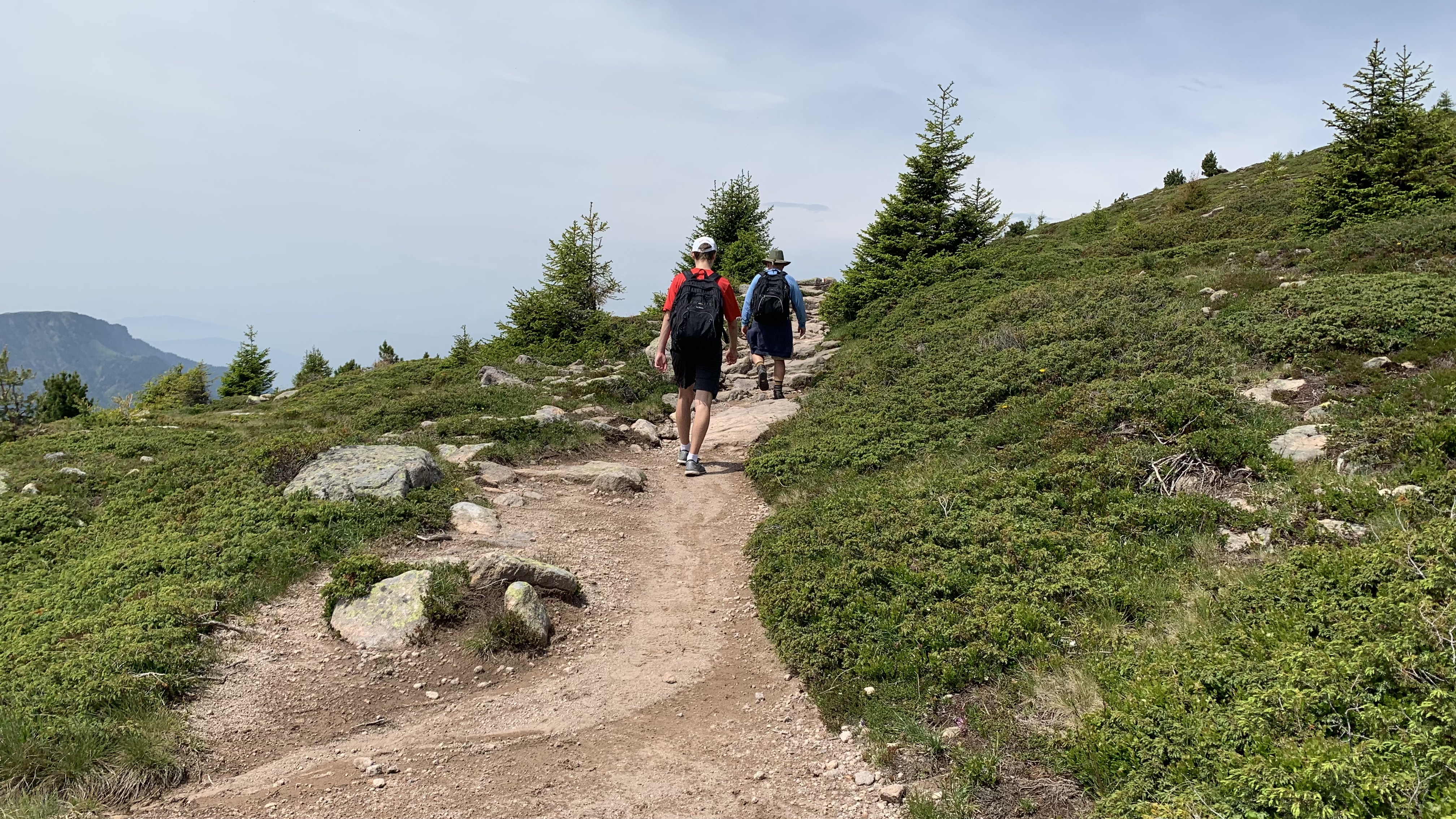 two hikers walking uphill on a trail